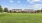 a large green field with houses in the background