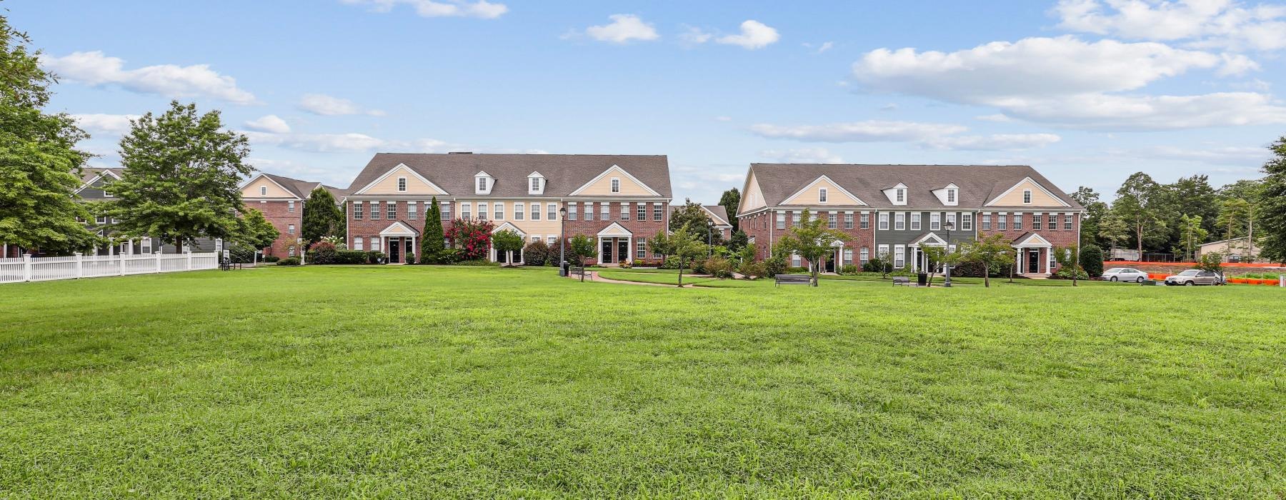 a large green field with houses in the background